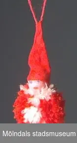 Julgranskarameller, tomtar och äpple tillverkade som pysselarbete, sannolikt på Katrinebergs daghem. MM02368:1 julgranskaramell i rött och vitt silkespapper med tomteansiktebokmärke på. Centimeterbreda veckade pappersremsor i ändarna. L: 590 mm. Diam: 50 mm.:2 Julgranskaramell i vitt och rött, som tomte med påmålat ansikte. L: 280 mm.Bredd: 60 mm.:3 Tomte av garnboll och rosa flörtkula. L: 180 mm. Diam:50 mm.:4 Tomte av rött vikt papper och bomull. L: 110 mm. Bredd: 65 mm.:5 Tomte av tallkotte, vit flörtkula och rött crépepapper. L: 150 mm.:6 Julgransäpple av röd flörtkula. L: 50 mm.:7 Hjärta av flätat halmband. L: 140 mm. B: 70 mm.Gåva av Katrinebergs Daghem genom Birgitta Bilting.