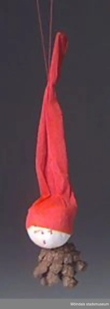 Julgranskarameller, tomtar och äpple tillverkade som pysselarbete, sannolikt på Katrinebergs daghem. MM02368:1 julgranskaramell i rött och vitt silkespapper med tomteansiktebokmärke på. Centimeterbreda veckade pappersremsor i ändarna. L: 590 mm. Diam: 50 mm.:2 Julgranskaramell i vitt och rött, som tomte med påmålat ansikte. L: 280 mm.Bredd: 60 mm.:3 Tomte av garnboll och rosa flörtkula. L: 180 mm. Diam:50 mm.:4 Tomte av rött vikt papper och bomull. L: 110 mm. Bredd: 65 mm.:5 Tomte av tallkotte, vit flörtkula och rött crépepapper. L: 150 mm.:6 Julgransäpple av röd flörtkula. L: 50 mm.:7 Hjärta av flätat halmband. L: 140 mm. B: 70 mm.Gåva av Katrinebergs Daghem genom Birgitta Bilting.
