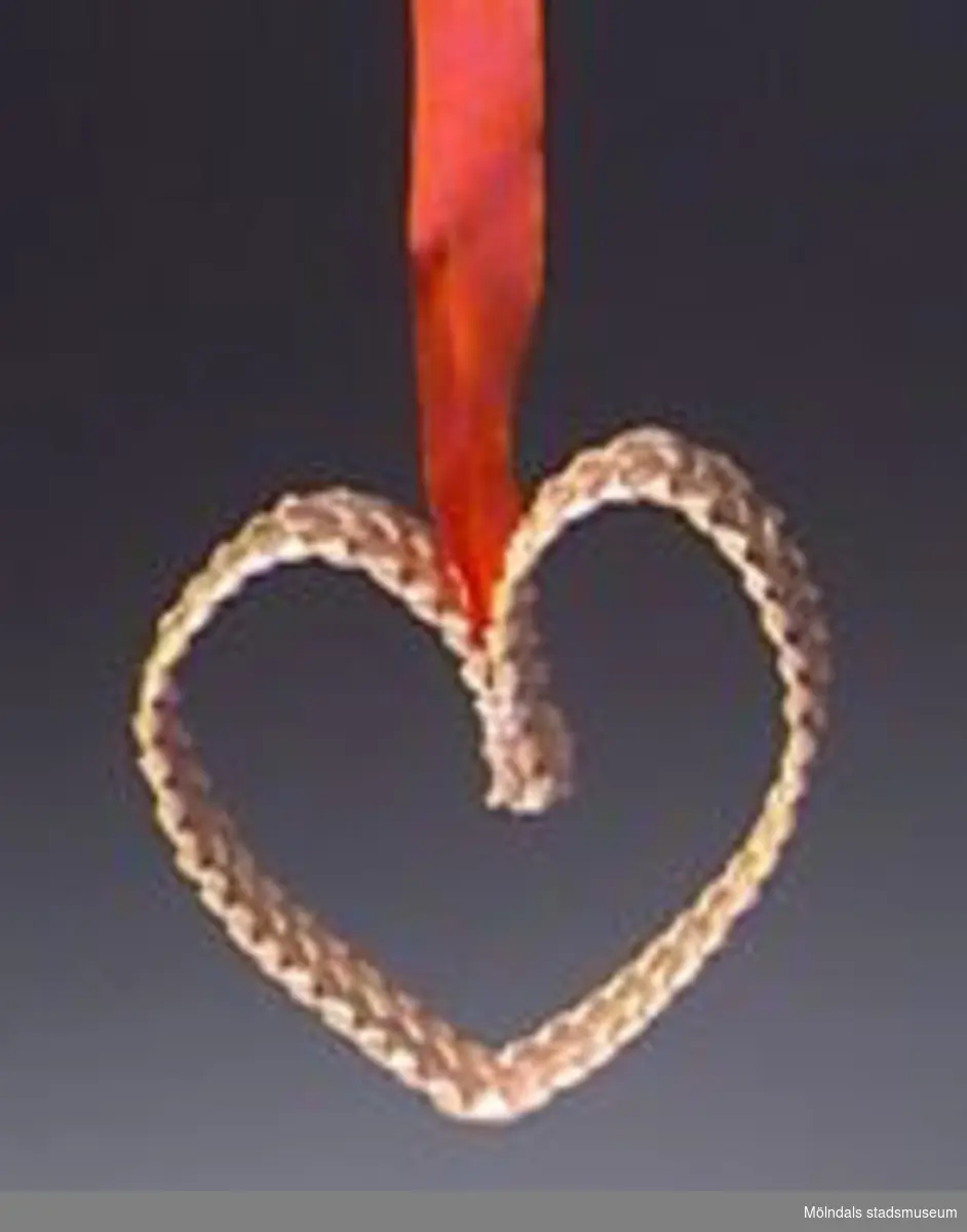 Julgranskarameller, tomtar och äpple tillverkade som pysselarbete, sannolikt på Katrinebergs daghem. MM02368:1 julgranskaramell i rött och vitt silkespapper med tomteansiktebokmärke på. Centimeterbreda veckade pappersremsor i ändarna. L: 590 mm. Diam: 50 mm.:2 Julgranskaramell i vitt och rött, som tomte med påmålat ansikte. L: 280 mm.Bredd: 60 mm.:3 Tomte av garnboll och rosa flörtkula. L: 180 mm. Diam:50 mm.:4 Tomte av rött vikt papper och bomull. L: 110 mm. Bredd: 65 mm.:5 Tomte av tallkotte, vit flörtkula och rött crépepapper. L: 150 mm.:6 Julgransäpple av röd flörtkula. L: 50 mm.:7 Hjärta av flätat halmband. L: 140 mm. B: 70 mm.Gåva av Katrinebergs Daghem genom Birgitta Bilting.