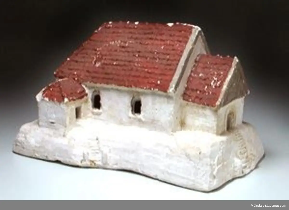 Gipsmodell av Kållereds kyrka. Vitmålad med rött tak. Gjuten efter en form gjord av bildhuggare Gunnar Johansson (1902 - 1969), Alkegatan 6 i Kikås, Mölndal.Tillvaratogs på Ryetskolans vind 1994 av Lars Gahrn.