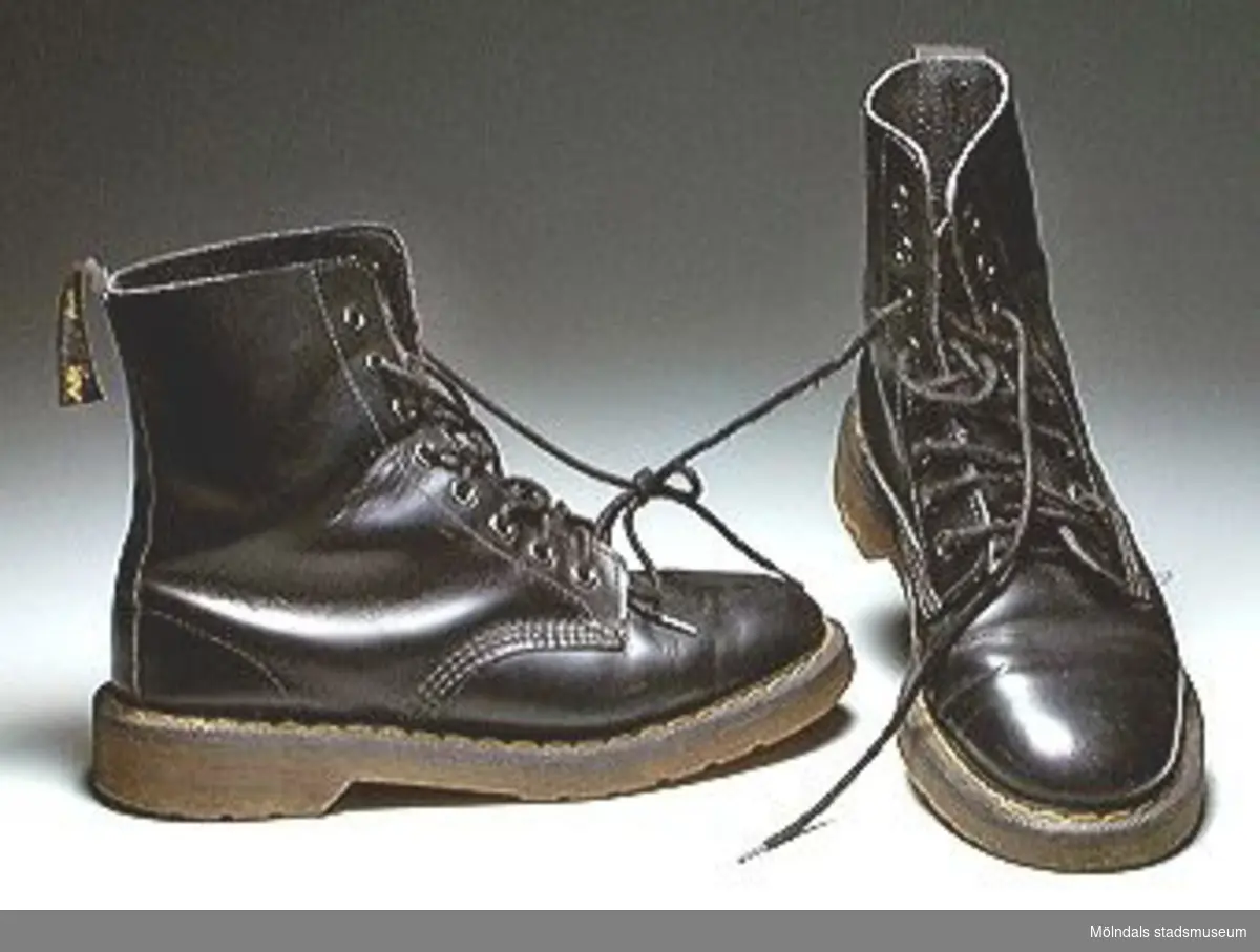 Svarta Dr Martens-kängor. Märkta: Air soles, cushion. Storlek 5. 
Till utställningen "Krinoliner och kortkort" på Mölndals Museum 5 feb. 1995 - 26 nov. 1995.