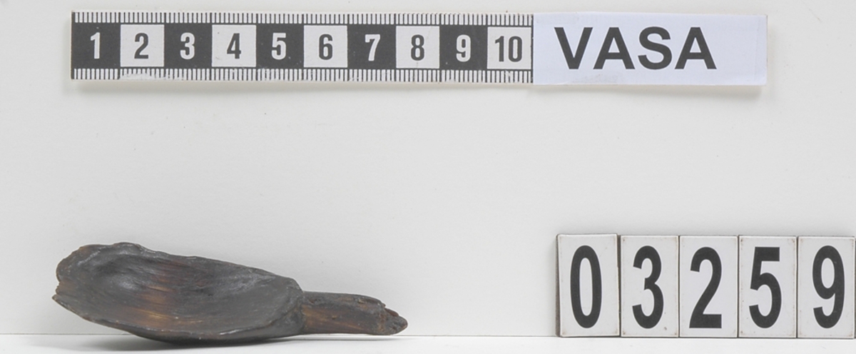 En träsked.
Ursprungligen har skedbladet troligtvis varit relativt brett, i förhållande till skaftet. Skedbladets undersida är åsformad. Skedskaftet är smalt, med ovalt tvärsnitt.
Skeden är mycket sliten. Skaftet är brutet, liksom skedbladets övre kant samt ena långsida.
