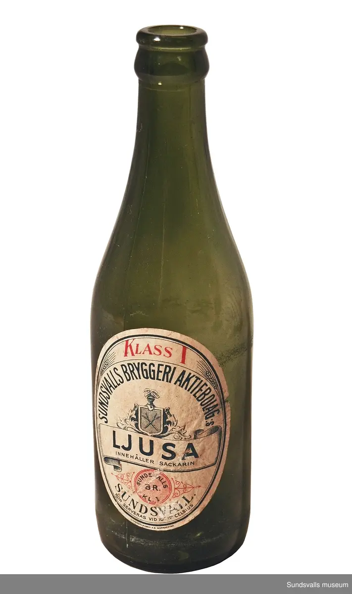Fem flaskor 'Sundsvalls bryggeri aktiebolag:s LJUSA'. De brungrönfärgade glasflaskorna är försedda med etiketter i vitt med blå och röd text. På etiketten kan man läsa 'KLASS 1, SUNDSVALLS BRYGGERI AKTIEBOLAG:S LJUSA, INNEHÅLLER SACKARIN, SUNDSVALLS BR. KL.1, SUNDSVALL, BÖR SERVERAS VID 10 GRADER CELSIUS'. Etiketten är tillverkad på Lithografiska AB i Norrköping. En av flaskorna har märkningen 'A 1/3 LIT' i relief.