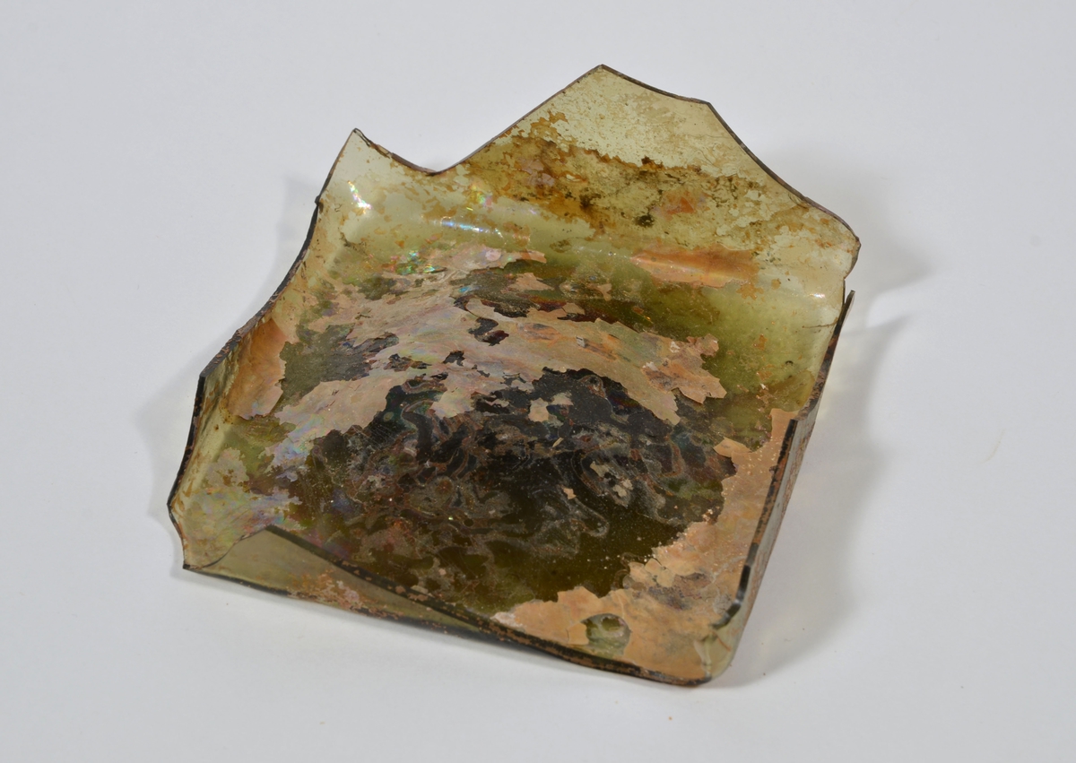 Botten till fyrsidig glasflaska. Glaset är grönfärgat.

2015: 05549a broke into three smaller pieces during handling, labled 05549 a, b, c. 05549a-d have moderate scaling.  All pieces are light green in color, and 05549d has pontil mark.