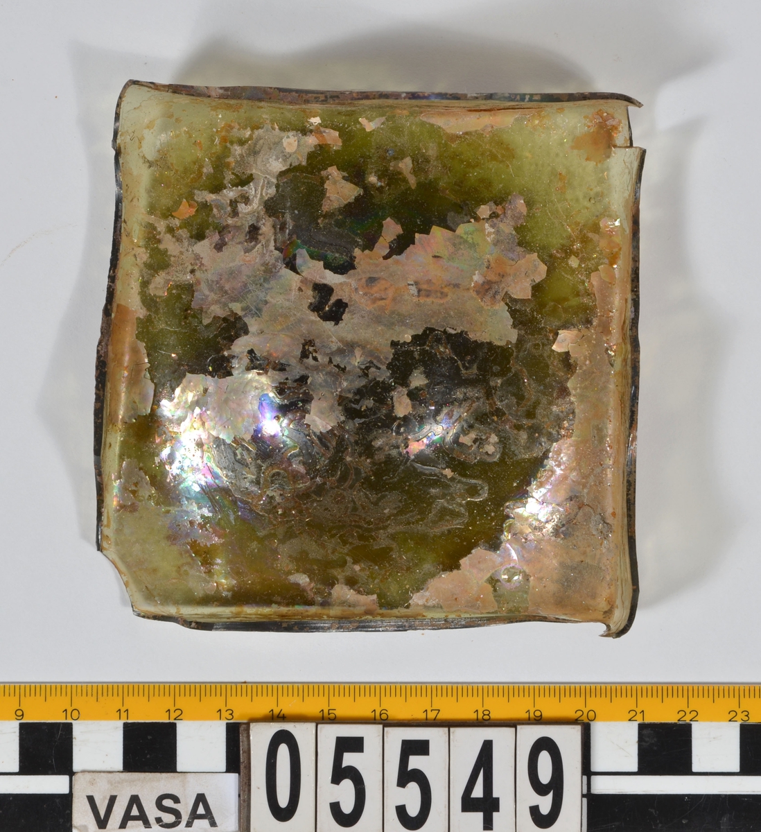 Botten till fyrsidig glasflaska. Glaset är grönfärgat.

2015: 05549a broke into three smaller pieces during handling, labled 05549 a, b, c. 05549a-d have moderate scaling.  All pieces are light green in color, and 05549d has pontil mark.