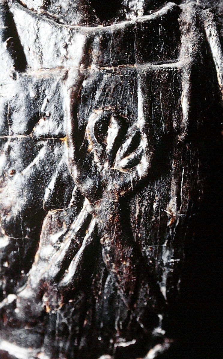 Skulptur föreställande en mansfigur med ett långsmalt och skäggigt ansikte, under en hög, slät hjälm med stora plymer. Runt hjälmen är en stålkrona trädd. Bakom huvudet skymtar ett snäckskal. Figuren är iförd en rikt ornerad rustning av thoraxmodell. Utefter figurens rygg hänger en mantel, som också draperar den vänstra axeln.

Hela figuren är frontalt framställd. Höger arm hålls lätt böjd utefter sidan, med handen fattande om ett svärdsfäste. Vänster arm är något böjd rakt ut från sidan, och handen verkar fatta tag om manteln. Kroppstyngden är jämnt fördelad på båda benen.

Figuren står på en sockel, vilken pryds av en bred och grimaserande maskaron. Sockeln är även försedd med en banderoll som tycks helt slät och utan namninskription.

Upptill är bakstycket framdraget i en kraftig "huvudplatta". Skulpturens baksida uppvisar tre snedställda, olika djupt liggande fält. Fälten, som utgör anliggningsytor, ger skulpturen en trappstegsformad profil.
Huvudplattan är delvis skadad. Svärdets klinga saknas. I övrigt är skulpturen relativt välbevarad.

Text in English: A sculpture representing a male figure with a long and narrow face that is bearded and has a moustache. On the head there is a plumed helmet on which a crown with points has been placed and behind the head a large sea shell. The figure is wearing richly decorated thorax type armour. The mantle is hanging down the back and draped over the left shoulder.

The figure faces towards the front. The right arm is slightly bent and held at the side and the hand holds a sword hilt. The left arm is slightly bent and held out from the side and the left hand seems to hold the mantle. The weight of the body is carried on both legs.

The figure stands on a plinth with a broad and grimacing mask and also has a label which is quite smooth and without any inscription.

The upper part of the back extends obliquely upwards in a powerful "head board". The sculpture''s back has three obliquely placed surfaces of different depths that are areas of attachment. The surfaces make the sculpture look like a step-ladder in profile.
The board behind the head is partly damaged and the blade of the sword is missing but otherwise, the sculpture is rather well preserved.