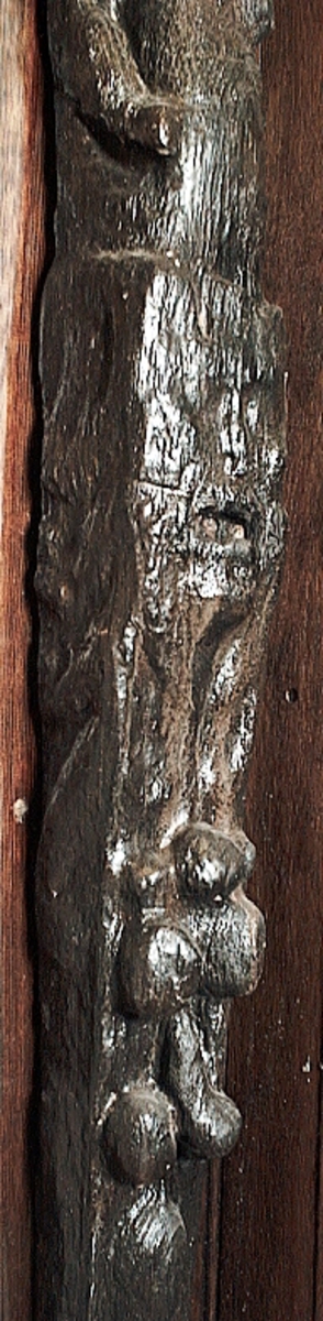 Skulpterad pilaster utformad som en karyatid med långt hår, troligen placerad under ett joniskt kapitäl.
Huvudet är vridet åt vänster. Höger arm är sträckt utefter sidan. Vänster arm är böjd och i handen håller figuren ett okänt föremål.
Pilasterskaftet är upptill prytt med en maskaron med bred, öppen mun och nedtill med en tung fruktfeston. Det nedåt avsmalnande pilasterskaftet avgränsas från piedestalen av en enkel vulst eller list med uppdragna kanter. Piedestalen är hög och jämnbred samt prydd med ett litet huvud och avslutas nedtill med en förtjockad bas. Skulpturens baksida är slät.
Skulpturen är kraftigt sliten och nött med finare detaljer utplånade.

Text in English: Sculpted pilaster with Caryatid with long hair under what is possibly an Ionic capital.
The head is turned to the left, the right arm is streched along the side, the left arm is bent and the hand holds an unknown object.
The shaft of the pilaster is decorated above with a mask with a broad, open mouth, below is a heavy festoon of fruit. The shaft tapers downwards and is divided from its pedestal by a simple torus or batten with drawn-up edges. The pedestal is high and even in width and decorated with a small head. It terminates at the bottom in a thickened base. Its back is smooth.
The sculpture is much worn, with finer details obliterated.