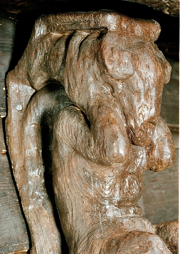 Skulptur föreställande en djävulsfigur i starkt hukande ställning, placerad på en hög sockel.
Figurens huvud är utrustat med stora, krumma horn. I vardera handen håller den på ömse sidor av huvudet något som möjligen kan tolkas som en stor snäcka eller lur. Hakan pryds av ett bockskägg. Figuren har fladdermusvingar på ryggen och starkt luden underkropp med klövförsedda bockfötter. Fötterna vilar på den starkt sluttande sockeln, som framtill är prydd med en ap- eller lejonliknande maskaron med stor nos och hög, välvd panna. På sockelns sidor ses voluter.
Sockeln utgör fortsättning på det kraftiga klink-konstruerade bakstycket som är framdraget ovanför figuren.
Skulpturen är delvis kraftigt sliten och vittrad, särskilt den övre delen. Nederdelen är något bättre bevarad.

Text in English: Sculpture of a devil figure in a crouched position, placed on a high socle.
The figure''s head is equipped with large, curved horns. In either hand the figure holds on either side of its head something that may possibly be identified as a large seashell or horn. The devil has a goat''s beard on its chin, bat wings on its back and very hirsute lower parts of the body, and cloven goats'' feet.
The feet rests on a sharply sloping socle that is decked in front with a mask of an ape-like or lion-like face with a large nose and a high arched forehead. On the sides of the socle volutes are visible.
The socle forms the extension of the heavy, clinker-built back-piece, which is drawn forward above the figure.
The sculpture, particularly its upper parts, is much worn and disintegrated. The lower part is somewhat better preserved.
