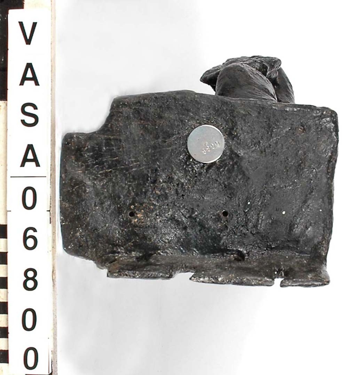 Skulptur föreställande en barnfigur spelande på en viola da braccio.
Fiolen hålles med vänster hand och stöder mot vänster knä. Kroppstyngden vilar på höger ben. Huvudet är vridet åt höger. Antydan till mantel utmed höger sida. Ovanför hjässan ses en äggstavslist. Figuren står på ett minimalt underlag som troligen avser att föreställa ett stycke naturlig mark. Skulpturens baksida är slät
Skulpturen är kraftigt sliten. Höger underarm är bortbruten.

Text in English: This is a sculpture of a child holding a viola da braccio in the left hand and supported on the left knee.
The weight of the body rests on the right leg. The head is turned to the right. There is the suggestion of a mantle on the figures right side. Just above the head, the back board comes forward at right angles and the front of the board is decorated with an egg moulding design. The figure stands upon a small plinth. The back of the sculpture is smooth.
The sculpture is very worn and the right forearm is broken off.