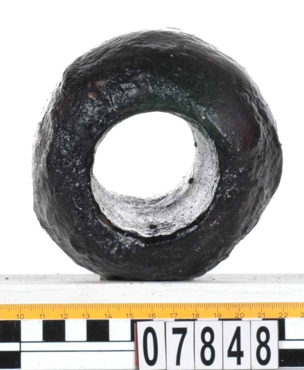 Rackklot. Runt svarvat klot med ett borrat genomgående hål. Eroderat. Asymetrisk form.