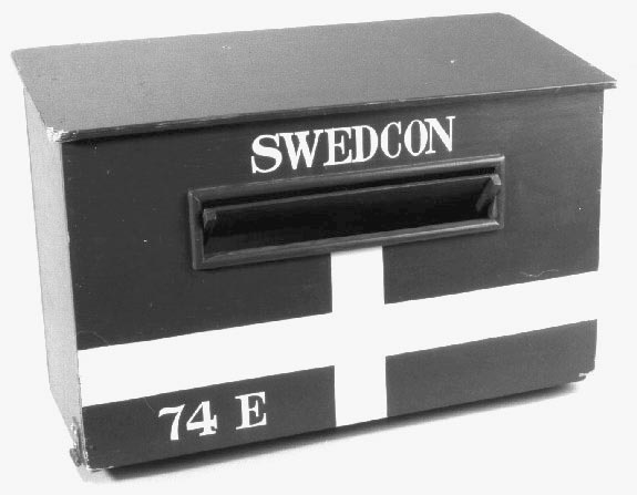 Brevlåda i trä med klaff för iläggsöppningen.
Iläggsöppningenhar mått:L=330 mm, H=40 mm. På fronten är lådan målad som den svenskaflaggan. Tömningslucka i botten, låsbar med hänglås.
