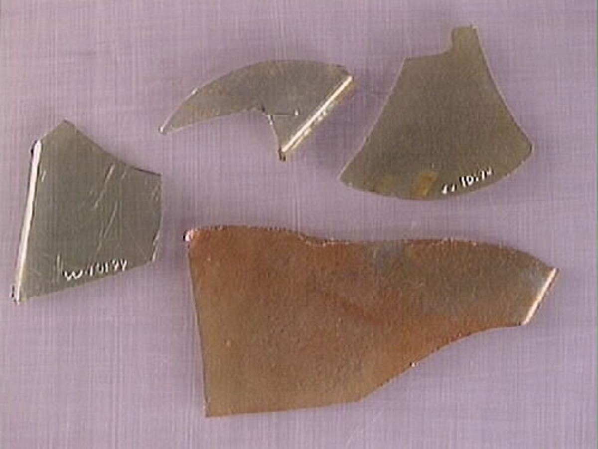 Botten samt fyra skärvor från fyrsidig flaska med stucken botten. På bottnens undersida finns ett puntelmärke. Glaset är grönfärgat och har en iriserande beläggning.

No damage. All pieces are a light green color and are from a case bottle.
10194a: has worn spot
10194c: Consists of two artifact numbers that have been glued together. Artifact has moderate scaling.