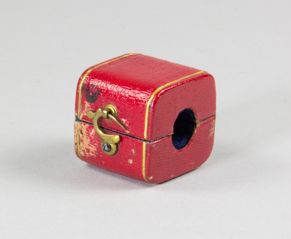 Etui av papp klädd utvändingt med rött läder, samt invändigt med blått sammet. Etuiet invändigt utformat för att omsluta ett sigills stämpelplatta. Ena kortsidan av etuiet med hål för sigillstampens skaft. Etuiet stängs med en liten böjd hasp av metall.