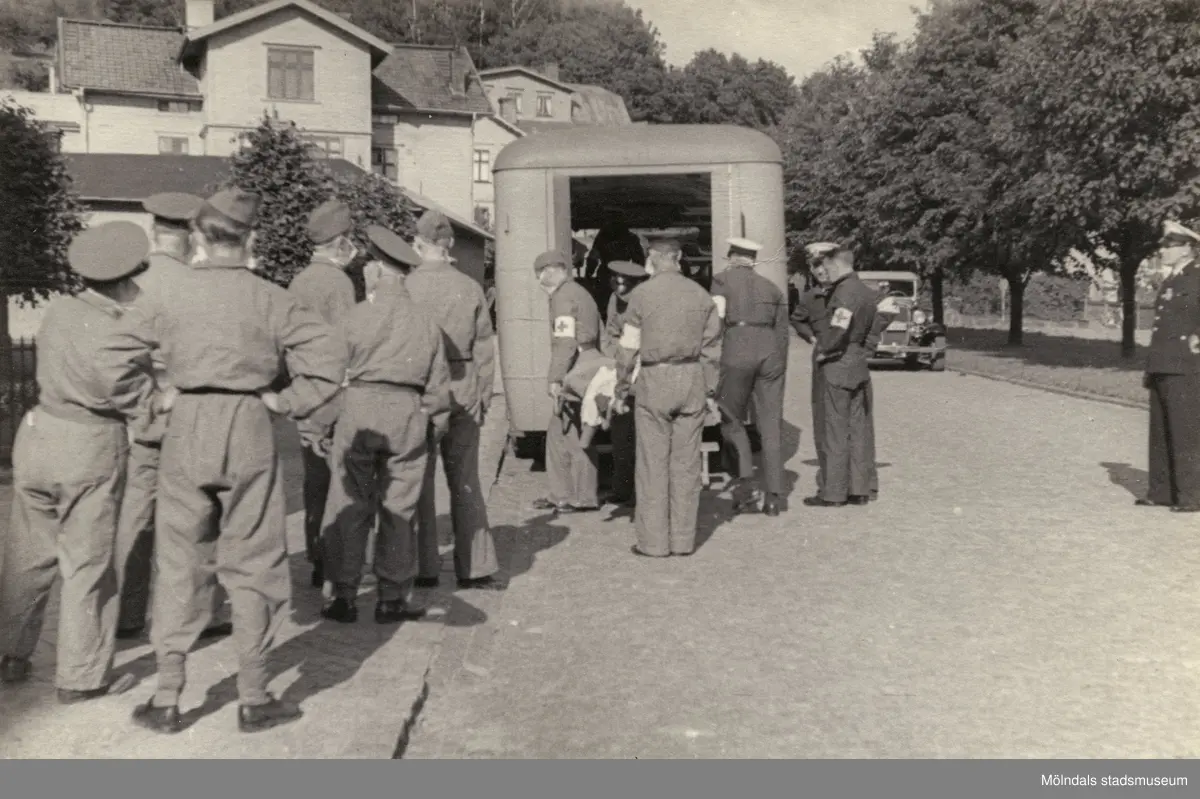 "Karantänsförläggning" på Kvarnbyskolan för överlevande från koncentrationsläger i Tyskland och Polen 1945.  
Skolan fungerade under denna sommar som beredsskapssjukhus.

Röda Korsets personal lastar ur bussarna/ambulanser.