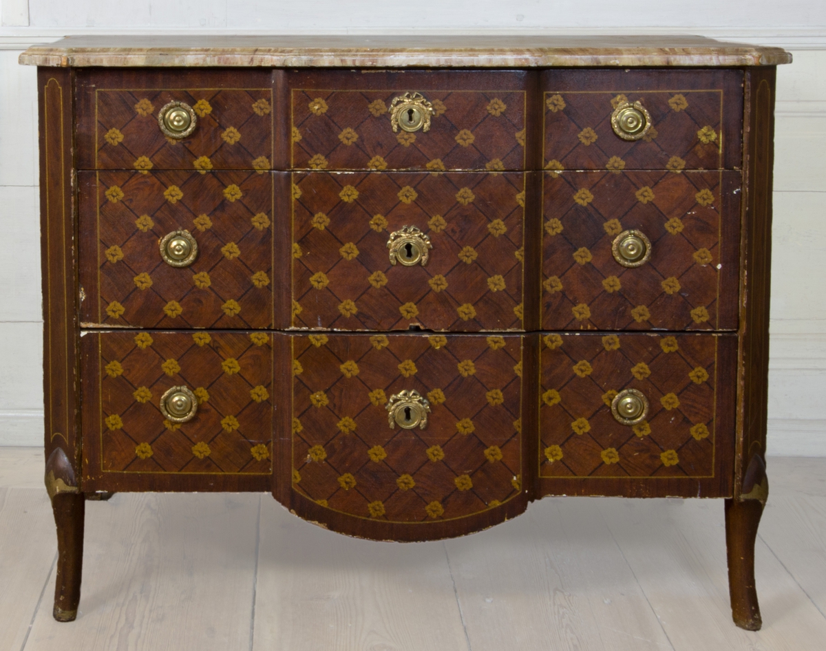 Byrå av furu, med imitationsmåleri som efterliknar fanér och inläggningar i olika träslag, i form av rutinläggningar och blommor. Med marmorerad skiva av trä. Rak form med avfasade hörn, med svagt svängda ben. Fronten med förkroppat mittparti, som nedåt avslutas i svagt bågformat undergehäng. Med tre lådor med nyckelbrickor med bandrosetter och beslag med dragringar i form av lagerkransar av förgylld mässing.