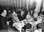 Postens Frimärkstryckeri  50 år.  Jubileumssupé för inbjudna på Postbankens restaurang, Drottninggatan 89, Stockholm. (Se Tidningen PS nr 6/1970).  Foto 13/5 1970.  Generaldirektör Nils Hörjel håller tal och lyssnar gör fr v Maj Bjurling, Lars-Erik Ewert, Stina Littke, Elis Reineck, Anna Stenfeldt, Sven Ådén, med ryggen mot kameran sitter Sven Rune Johansson och Birgit Nilsson.