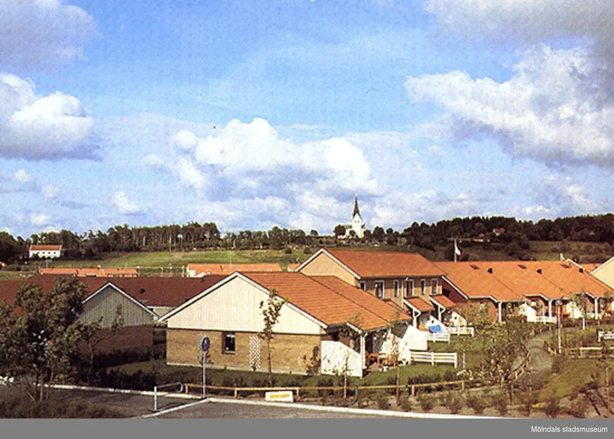 Vykort på bostadshus i Kyrkängen. Lindome kyrka syns i bakgrunden.