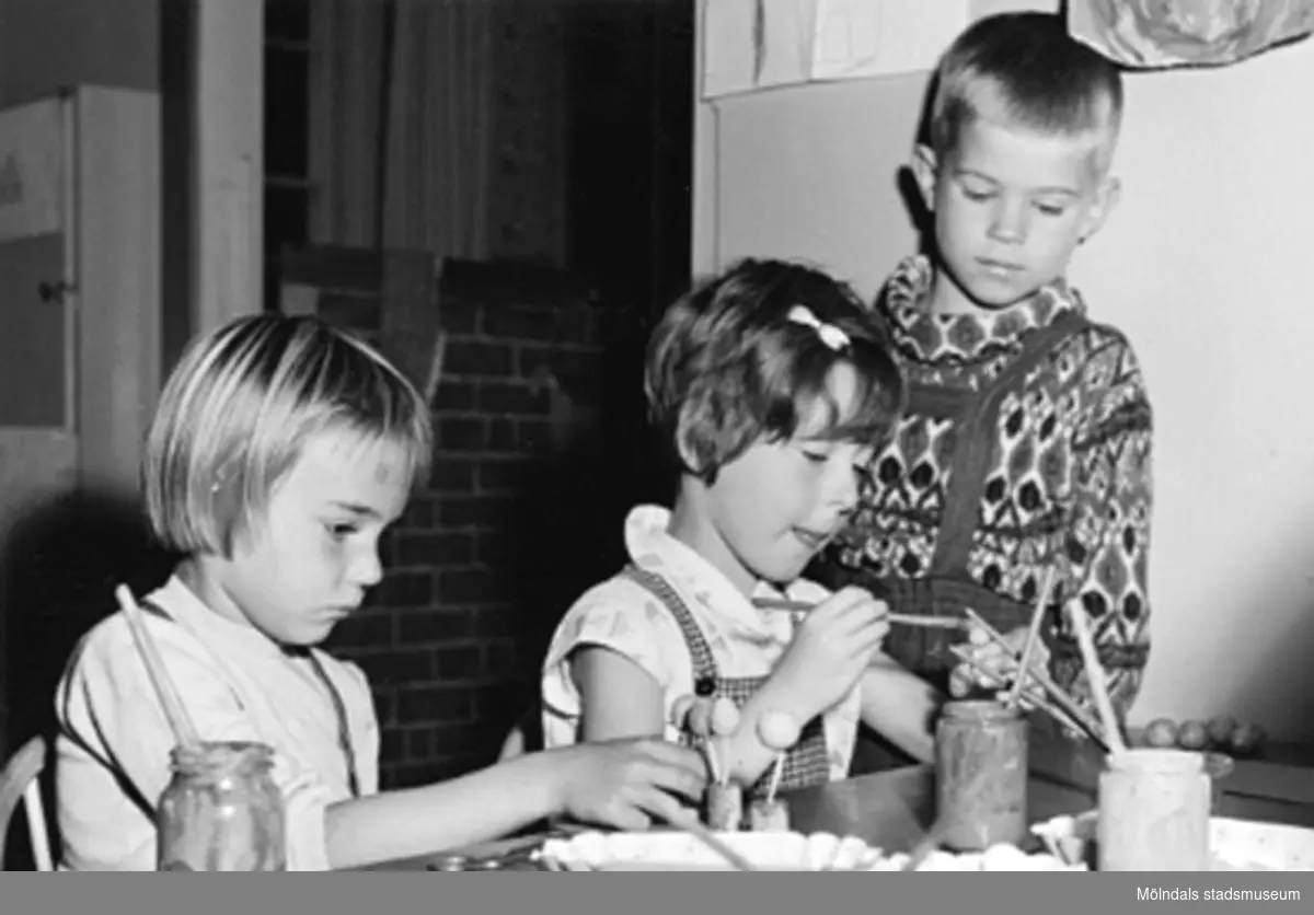 Tre barn som pysslar vid ett bord. Holtermanska daghemmet 1953.