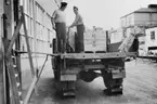 Pallarna med tidningsbuntarna körs över till en lastbil, vid
ICA-Kurirens lastbrygga, f.v.b. till järnvägen.