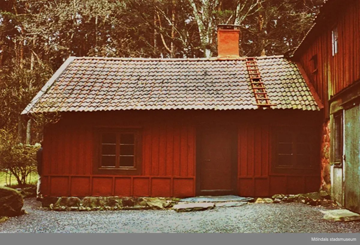 En röd liten stuga tillhörande en gård söder om Lunnagården - vid Sisjövägen, april 1993.