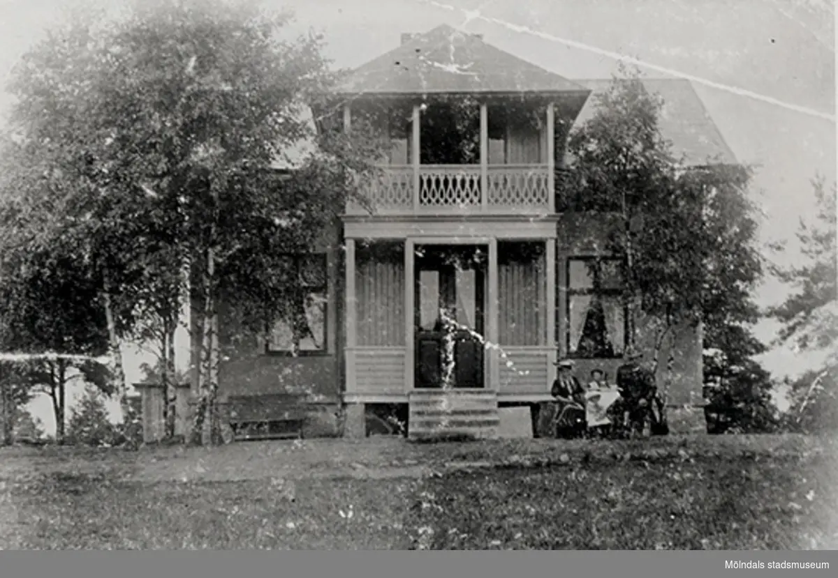 Zelma Flyrins speceriaffär (Lackarebäcks speceriaffär) på Skogsgatan 1 i Lackarebäck, omkring 1903 - 1910. Personerna på bilden är troligtvis Hilmer, Zelma, Harry och Gertrud eller Bertil Flyrin. Huset blev ombyggt 1910.