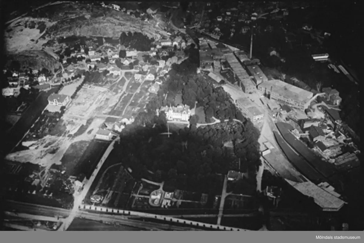 Flygfoto västerifrån över stadsdelen Trädgården och Papyrus troligtvis år 1923. Kvarnbyskolan håller på att byggas 1923 eller 1924. Mitt i bild ser vi Papyrus kontor (Villa Korndal) inbäddat i grönska. I husgruppen till vänster därom ses Apoteket (Kvarnbygatan 9) och ett hus där det under en tid fanns en tvättinrättning av något slag. Sist syns huset där restaurang Godhem inrymdes. På Papyrusområdet syns en byggnad i lite diagonalt läge som kallades för Kromo. Vägkorset i vänster underkant är blivande Mölndalsbro.