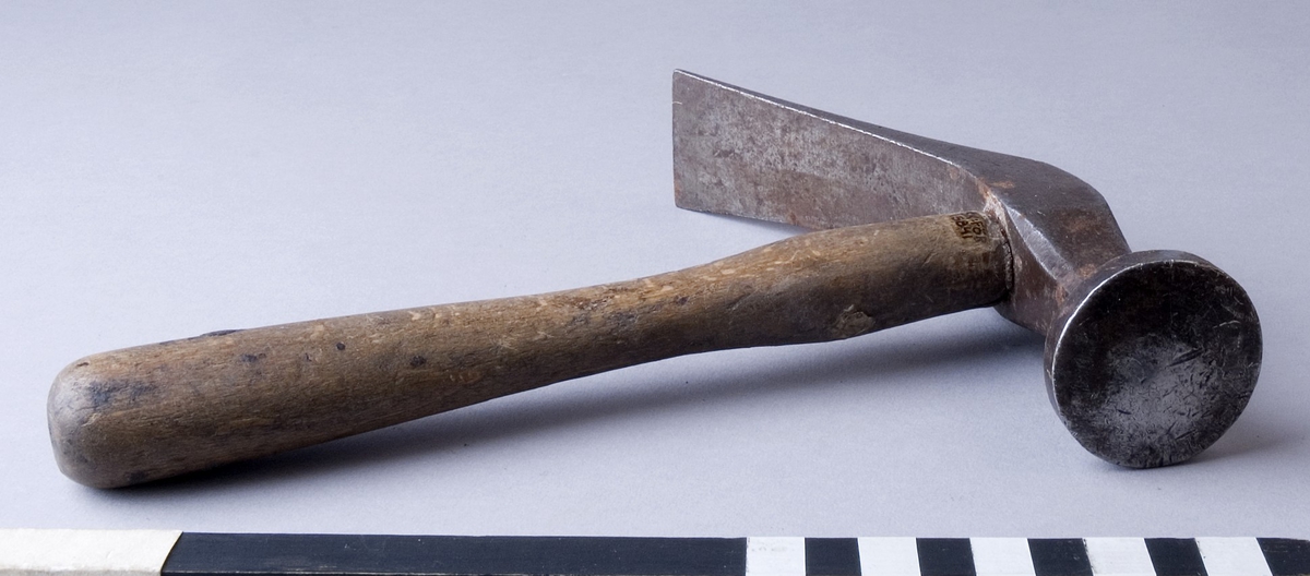 Hammare, skomakarhammare, fabriksgjord av stål med handtag av trä. Hammarens huvud är runt i ena änden och rak i den andra, något angripet av rost, samt märkt: "3".
Handtaget med fläckar av beck, samt med rest av ett fastsatt tryckt papper. Pappersbitens längd: 7 mm, bredd: 9 mm.