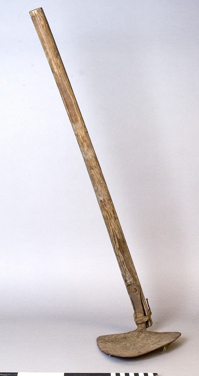 Hacka, med handtag av trä och blad av järn. Sedvanlig modell med trekantigt blad.