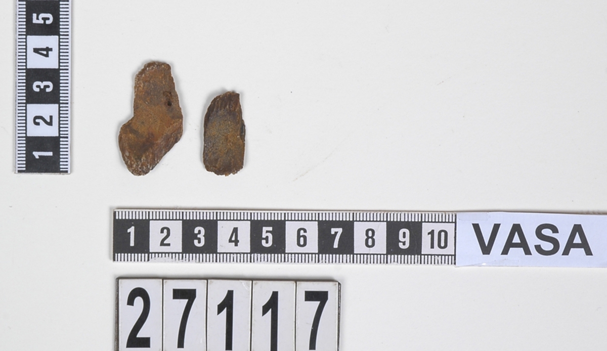 Delar av en träsked. Delarna utgör två mindre partier av skedbladet. I den ena delen syns ett litet runt hål.

Delarna är mycket slitna och fragmentariska.

För mer information se Dokumentationsblankett under Referenser – Länkade filer.