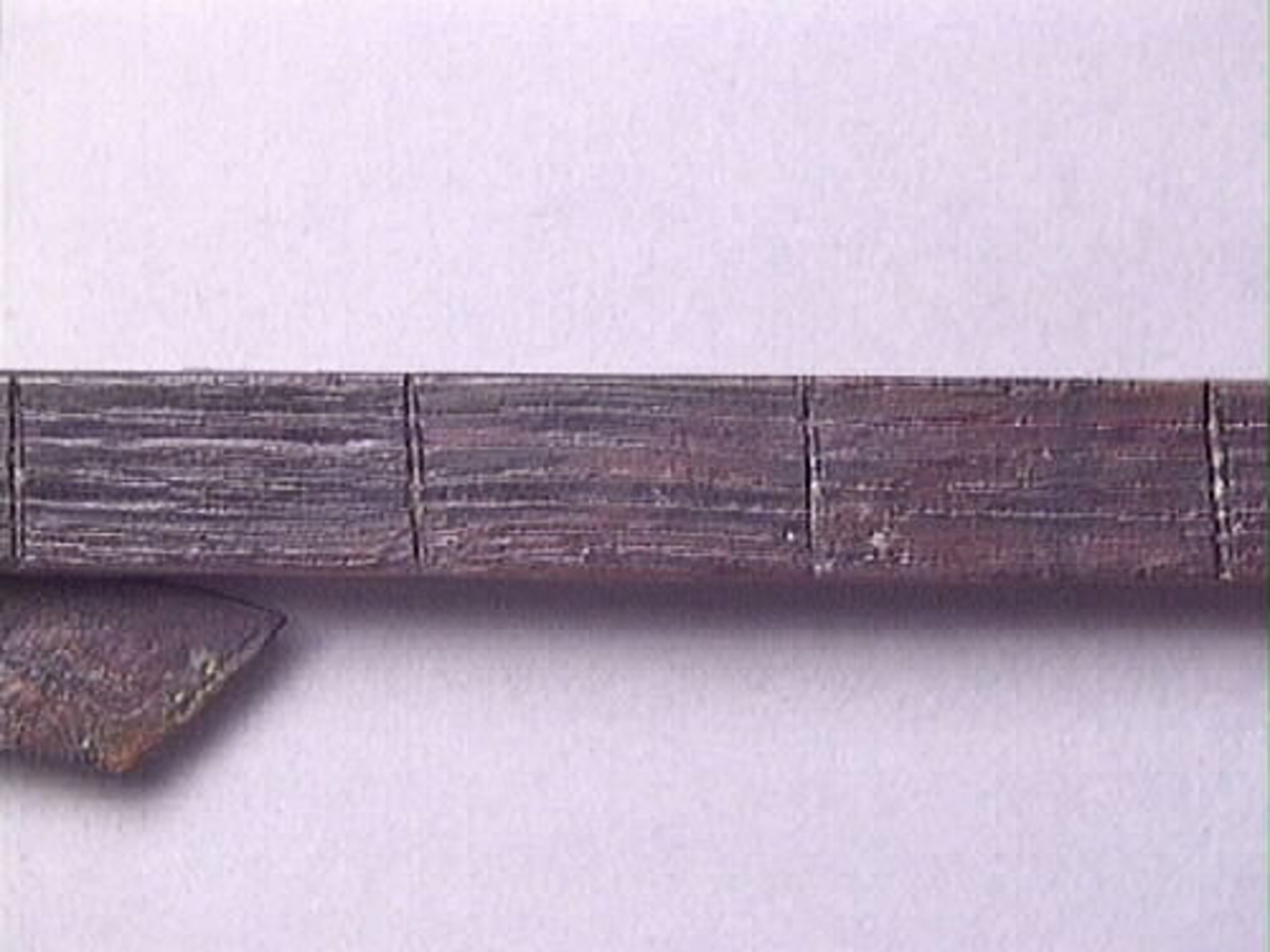 En vinkelhake, s k smygvinkel.

Skaftet är försett med sex stycken ristade skåror som markerar tum. I ena skaftänden sitter ett nytillverkat, ledat, järnblad. Bladet är fäst med en nytillverkad järnsplint. I skaftets ena ände, närmast bladet, löper en skåra eller ett spår. Spåret är mellan 68 och 80 mm djupt.

Smygvinkeln är i gott skick.

För mer information se Dokumentationsblankett under Referenser – Länkade filer.