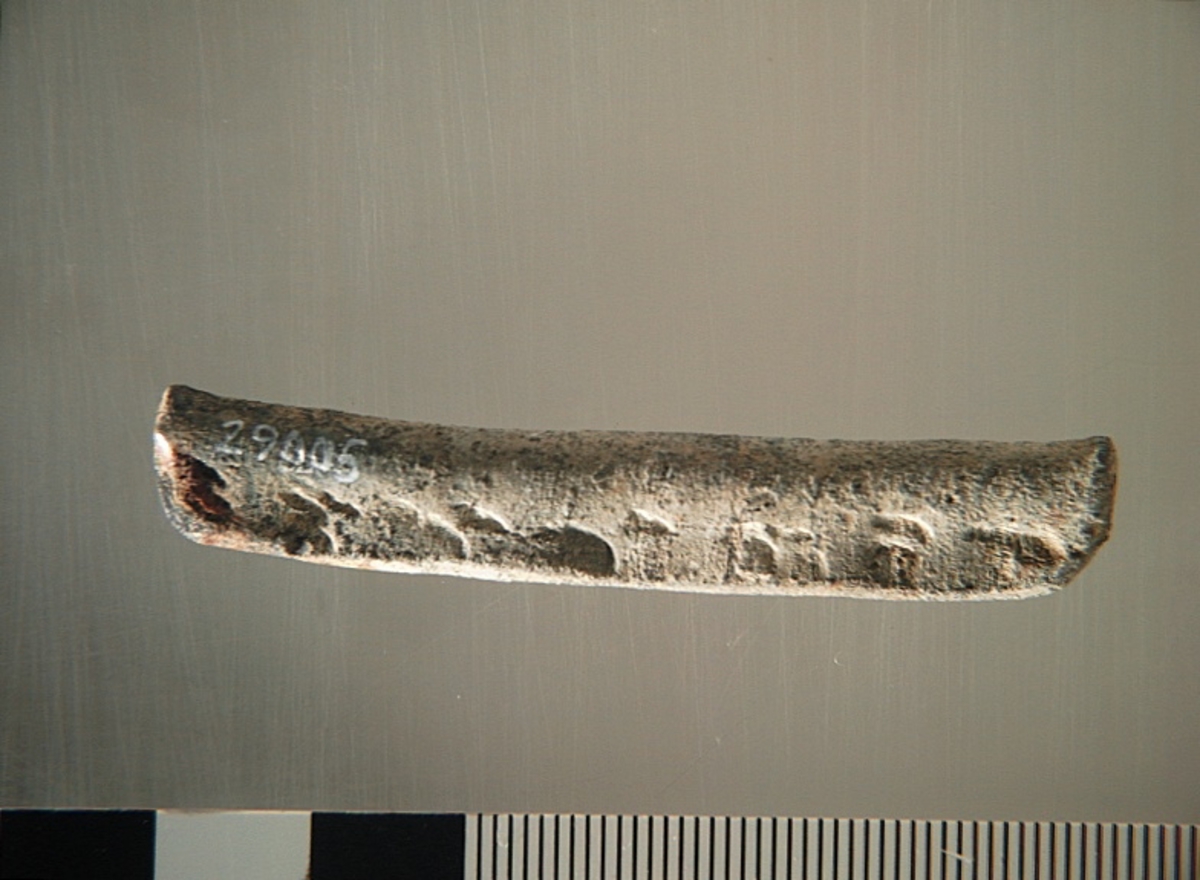 Sänket består av en vikt blybit. Sänket har tydliga märken efter det verktyg som pressat ihop sänket runt garntråden. Sänket är i gott skick.

Text in English: Lead sinker in the shape of a flat tube. The rectangular piece of lead is folded vertically in half and has visible tool marks from the folding process. The yarn is pushed through the hole. Grey mat in colour. In good condition.