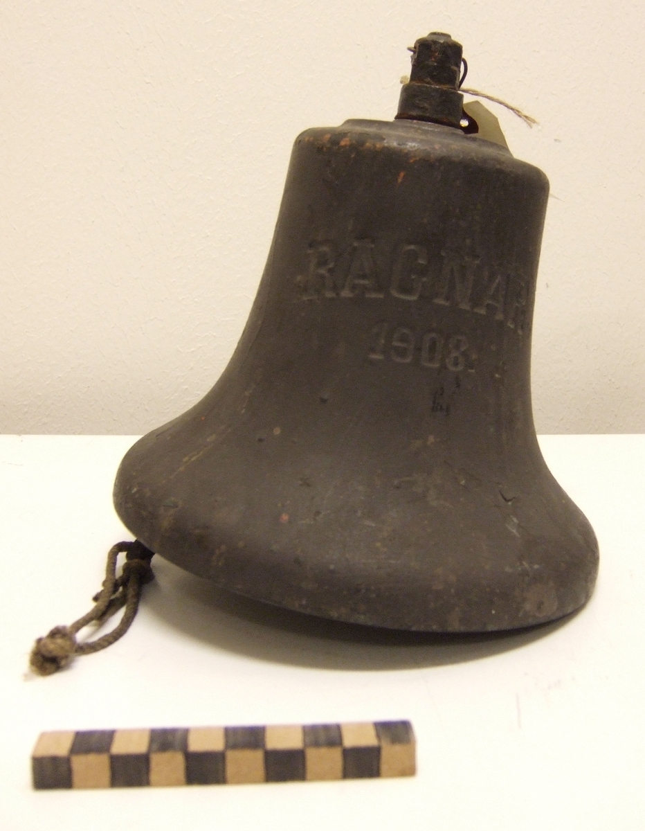 Skeppsklocka av brons, gråmålad. Märkning: "Ragnar 1908".
