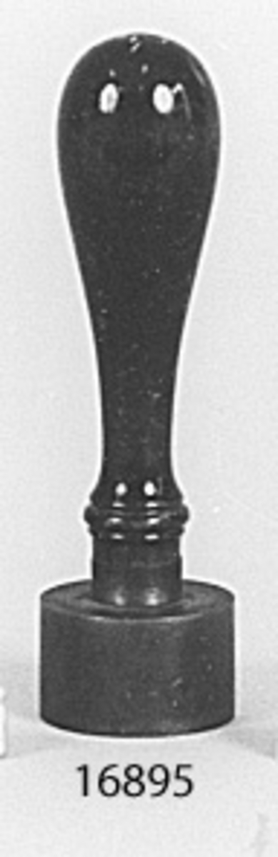 Cylindrisk stans. Svarvat, valnötslackerat handtag. Ingraverat = i mitten krönt ankare, omgivet av tre kronor. Text kring kanten = "H M Minsvepare Bremön". Det hela inom en ring.