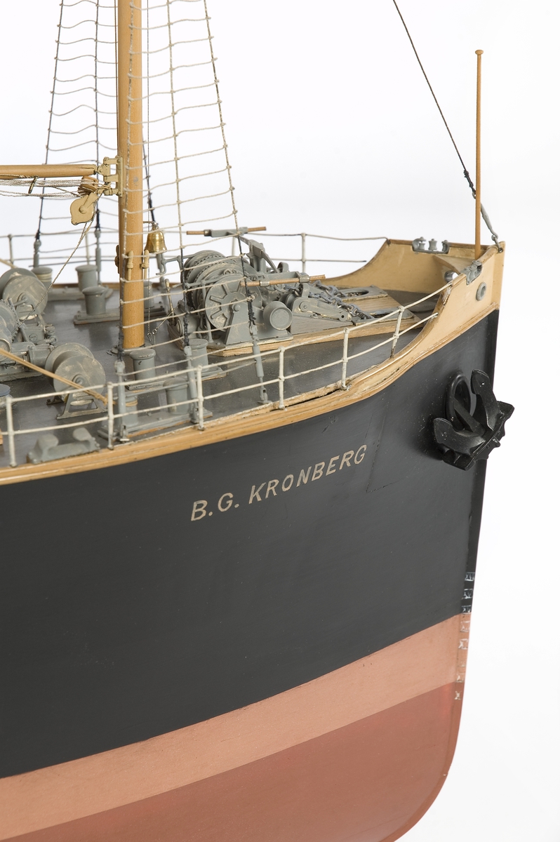 Modell av lastångfartyget B.G. Kronberg förande sommardäckslast av sågat virke. En besättningsmanspänner fast de kätingar som håller lasten på plats. Rak stäv, midskeppshus kommandobrygga,3 båtar i dävertar, poopdäck med däckshus, svart skorsten med 3 vita band och en cirkel, 4 master bommar.Svart skrov med rödbrun botten i två nyanser. Helmodell.