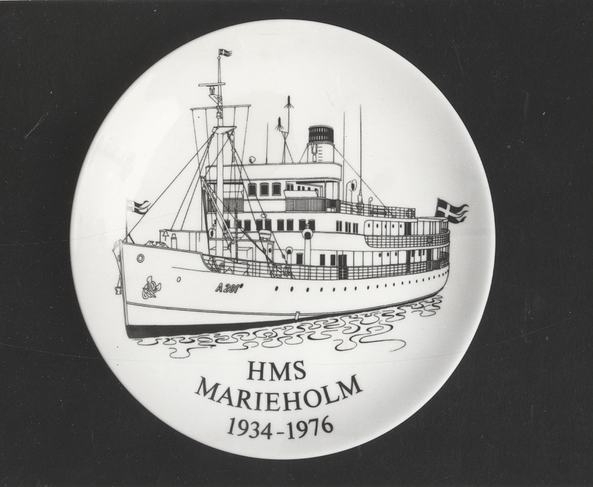 På framsidan bild av HMS MarieholmFramsida: HMS Marieholm 1934-1976Baksida : 1934 Byggd i Odense                  1935-40 I trafik för SAL                  1940       Inköpt av Kronan                  1940-49 Förbindelsefartyg i Kfl                  1950-57 Under vinterhalvåret                                      expeditionsfartyg för CKF                  1958-76 Stabsfartyg för CKFFöremålets form: Rund