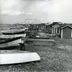 Sjöbodar och uppdragna båtar. Bilden strax norr om strandstället. Stranden mot Öresund. Skåne, Malmöhus län, Råå.