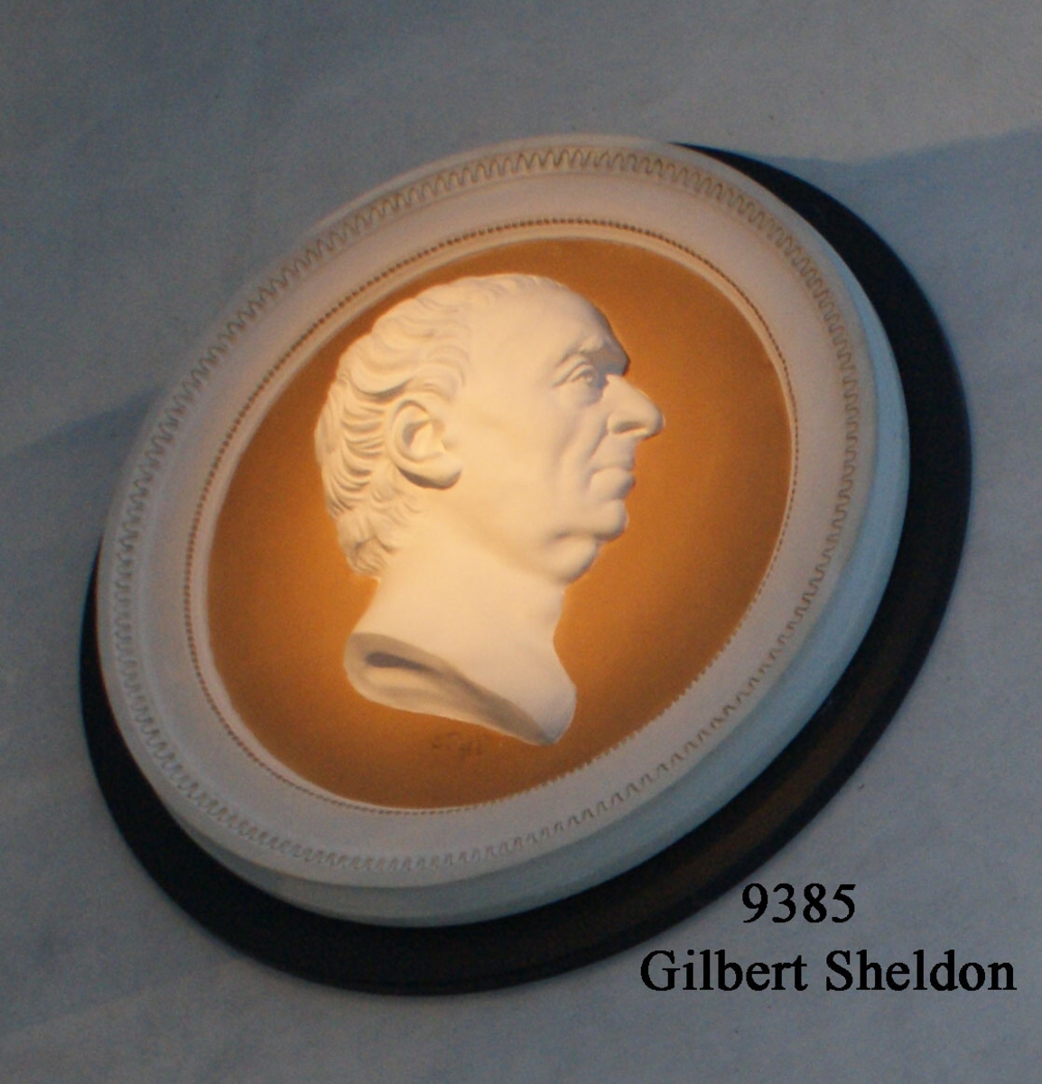 Medaljong i gips, föreställande Gilbert Sheldon.  Medaljongen en avgjutning av original, utförd av G. Bodini. Märkning: G.Bodini.