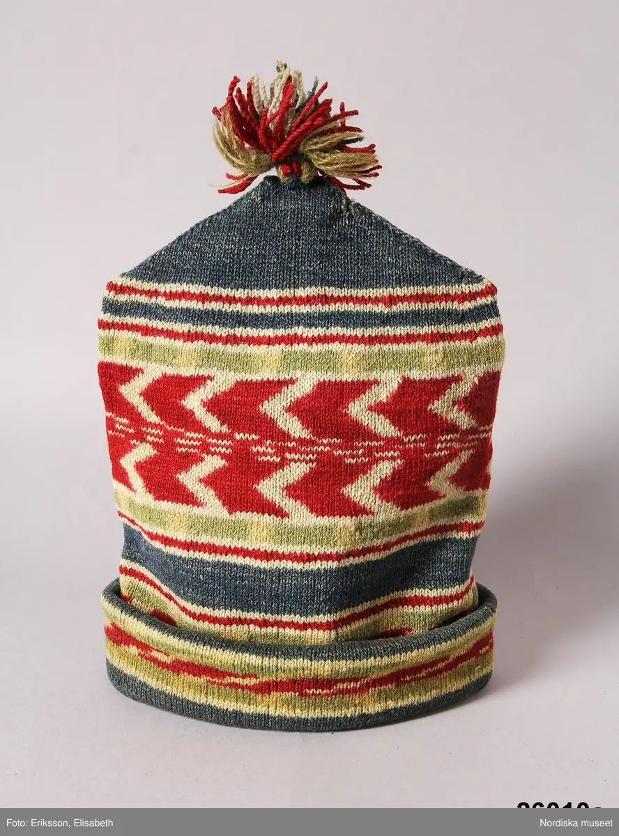 2 st röda toppluvor, A-B.
A.
B.Röd toppluva, maskinstickad i slätstickning av ullgarn, filtad, 2 stycken med nästan osynliga sidsömmar, hoptagningar i toppen. Liten röd ullgarnstofs högst upp. Nederkanten uppvikt 2 varv.

Berit Eldvik okt 2005