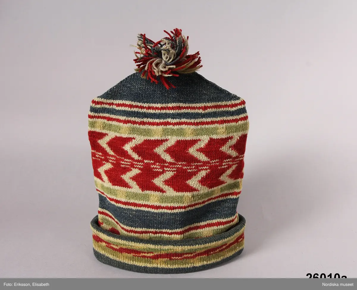 2 st röda toppluvor, A-B.
A.
B.Röd toppluva, maskinstickad i slätstickning av ullgarn, filtad, 2 stycken med nästan osynliga sidsömmar, hoptagningar i toppen. Liten röd ullgarnstofs högst upp. Nederkanten uppvikt 2 varv.

Berit Eldvik okt 2005