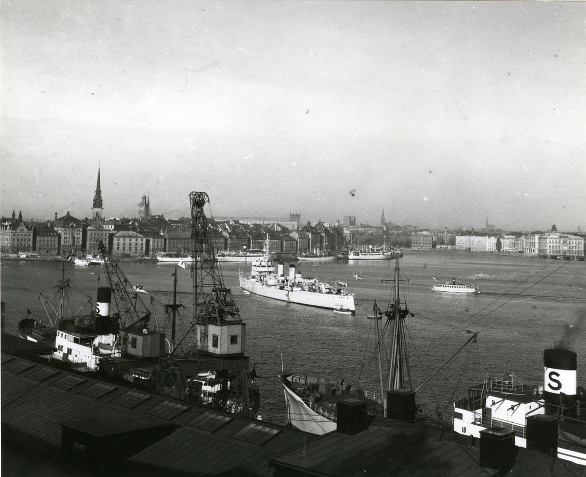 Kryssaren Fylgia på Stockholms ström. I förgrunden Svea-bolagets lastångfartyg i Stadsgården och i bakgrunden Skeppsbron med finlandsbåtarna.
