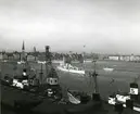 Kryssaren FYLGIA på Stockholms ström. I förgrunden Svea-bolagets lastångfartyg vid Stadsgården och i bakgrunden Skeppsbron med finlandsbåtar.