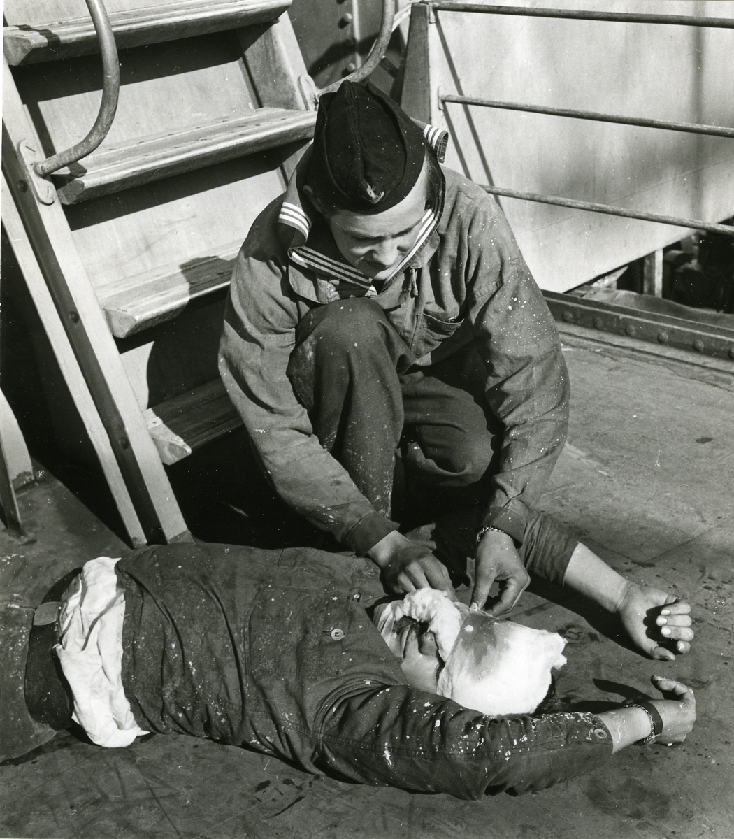 Stridssjukvårdstjänst ombord på kryssaren Tre Kronor, 1949. En man förbinder en "sårad".