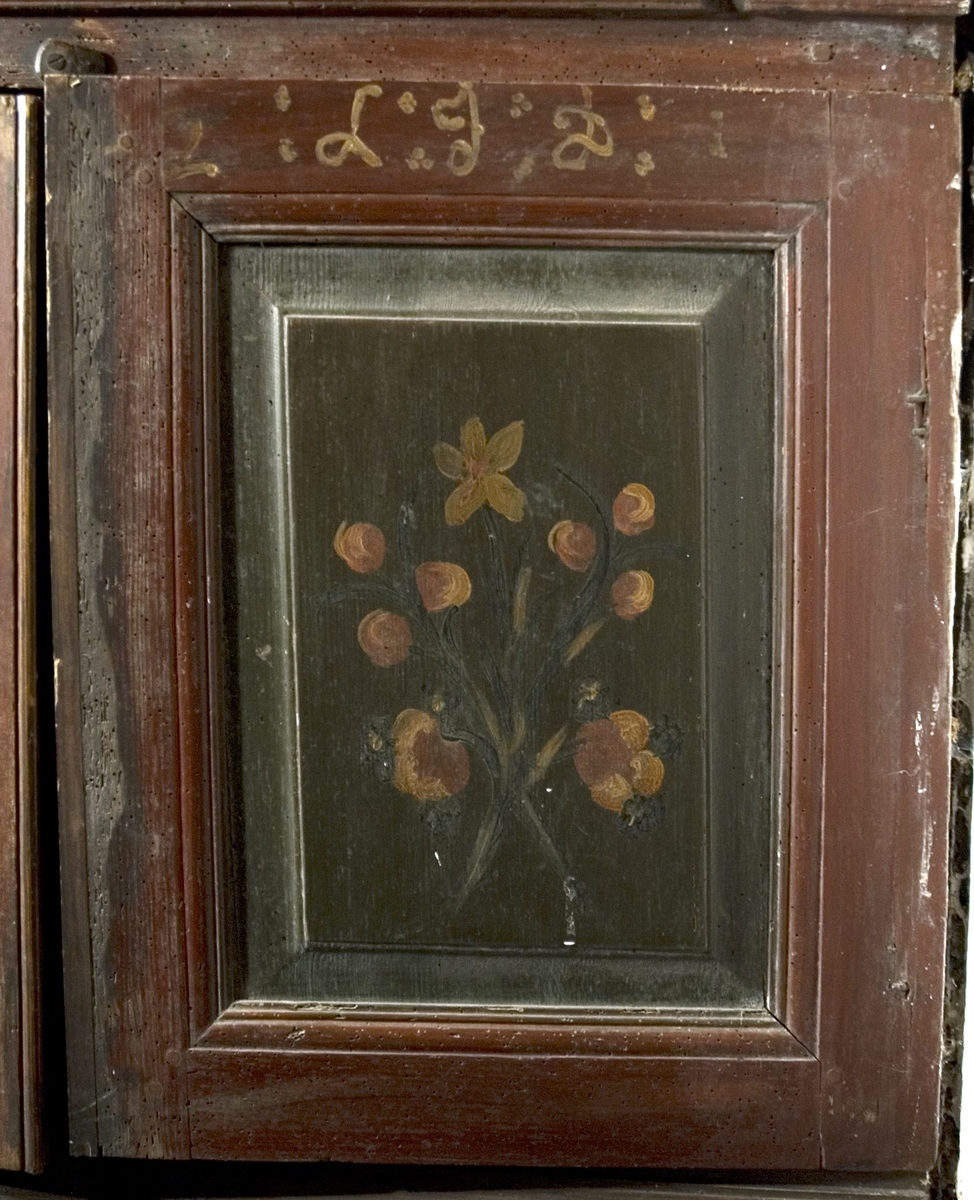 Skåpsäng, av trä. Profilerad ramlist upptill på fram- och sidostycke. Inget "innertak". Längs golvet en list med två utskurna hjärtan. Vid fotändens övre del finns ett skåp med två dörrar. Ett hyllplan i skåpet. Ovanför dörrarna finns en vridbar knopp för stängning. Nedanför dörrarna finns två fyllningar. Sängen är målad i brunrött med vissa detaljer och marmoreringar utförda i svart. Skåpdörrarnas fyllningar är målade med grönt som botten och därpå en enkel blombukett i vitt, rött och svart. Texten eller årtalet på höger dörr är bortnött, på vänster dörr står: L J D.