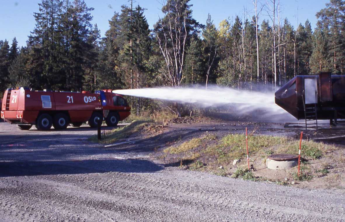 En rød brannbil spruter vann over "øvelse flyet" fra gardermoen flyplass, OSL.