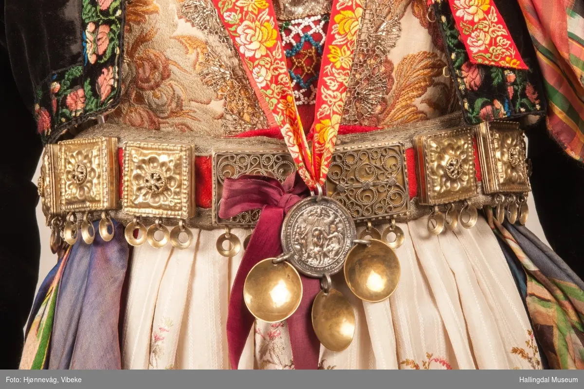 Drakten står utstilt i den faste bunadutstillingen på Hallingdal Museum, Nesbyen.  Den ble satt opp på grunnlag av et bilde fra Norsk Folkemuseum, tatt ang. av Axel Lindahl.  Tidfestet til 1877-78.  Høyde på overdel ble bestemt etter lengden på trøya.  Utelatelsen av det store bryststykket og andre forandringer ble diskutert med Ågot Noss og godkjent.  Ny dokke ble bygd opp med utgangspunkt i stakkens mål.
HFN 03387-stakk med liv.  Stakk og liv ble skilt 5.1.1999, rød ulltråd med tråklesting festet delene sammen, fjernet.  Stakk festet til liv i ny høyde med store attersting med rødt bomullsgarn.  Det ble sydd understakk i ubleket lerret med vattering av dacronvatt, for å få riktig profil.
HFN 03386 Forkle er noe for kort.
HFN ? Skjortering, sydd fast i skjorta.
HFN 00677 sølje, sydd fast i skjorta.
HFN 00533 sølje sydd fast i skjorta.
HFN ? Perleklut, sydd fast i skjorta.
HFN 00560 Angus Dei, påsatt ny silkesnor.
HFN 06695 Silketørkle, blått, festet i forklesnora
HFN 03499 Silketørkle festet i forklesnora
HFN 06694 Silketørkle, rødt rundt halsen
HFN 03603 Brudelue
HFN 03137 Stølebelte, påsatt bendelbånd, disse ligger over skuldrene for å holde beltet oppe.
HFN 03318 Linskjorte.  Vasket: desember 2000
HFN 01815 trøye i svart speilfløyel.