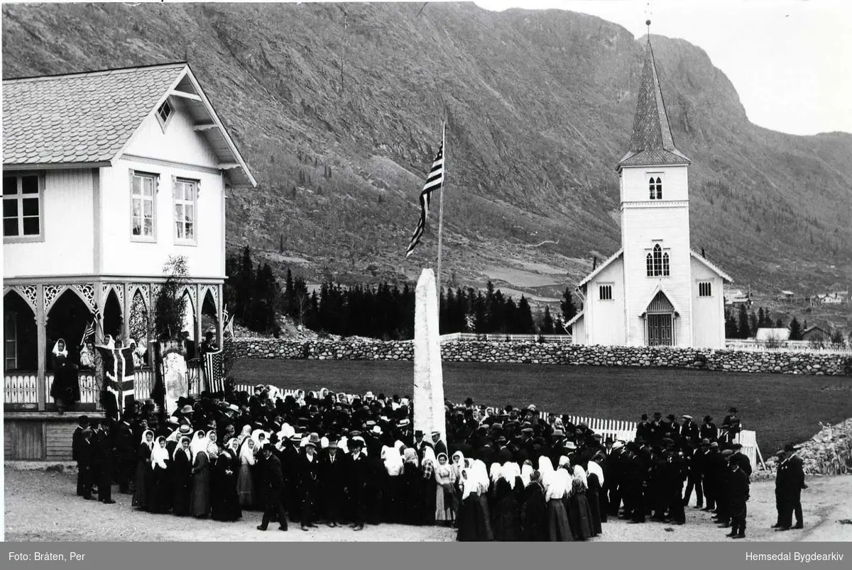 Jubileumsfesten 1914i Hemsedal. Folk er samla ved bautasteinen framfor det gamle kommunehuset som vart rive ca. 1980. Bautasteinen vart då flytta inn på kyrkjegarden framfor Hemsedal kyrkje som ein ser i bakgrunnen