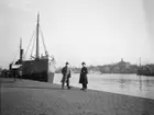 Två män på kajen vid Strandvägen, Stockholm.
I bakgrunden Skeppsholmen.