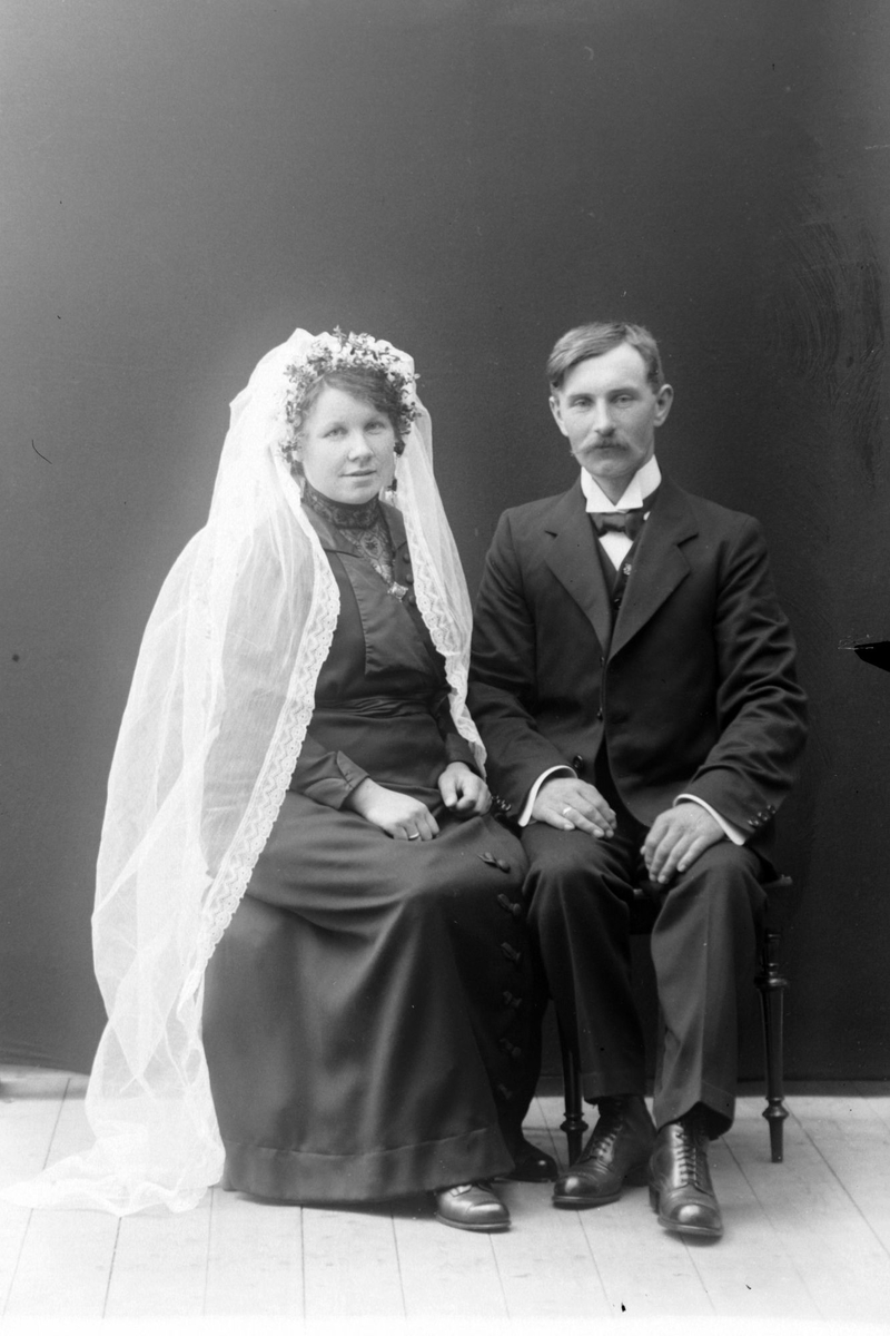 Brudepar studiofotografert i helfigur foran ensfarget bakteppe.
