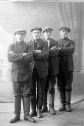 Studioportrett av fire menn i grove klær og skaftstøvler, og