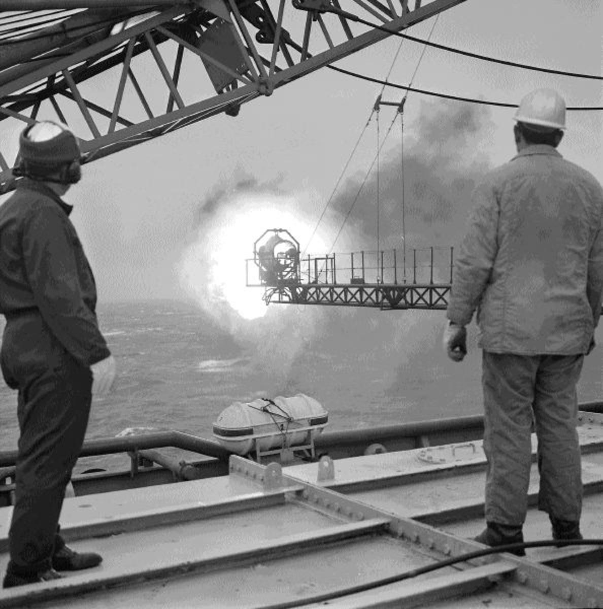 To menn studerer en flammebom på boreplattformen "Gulftide".